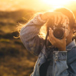 Beautiful woman taking picture outdoors with a analog camera