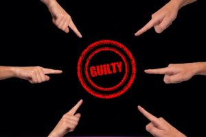 Plusieurs doigts pointent du doigt le mot guilty (coupable)